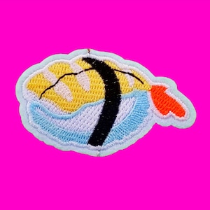 Peut inclure: Un patch brodé représentant un poisson de dessin animé en bleu, jaune, noir et orange avec un œil noir.