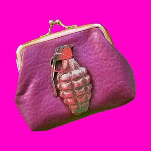 May include: A purple leather coin purse with a gold-colored zipper and a grenade charm.