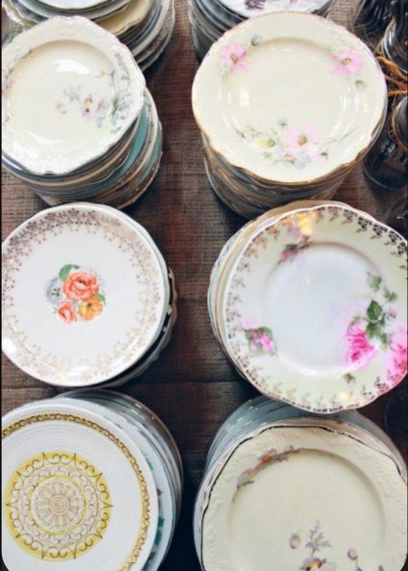 May include: A stack of vintage floral patterned plates with gold trim. The plates are in various sizes and feature different floral designs.