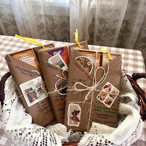 May include: A wicker basket holds several brown paper-wrapped packages, each tied with a yellow ribbon. The packages contain tea and are labeled with handwritten text and decorative stickers. The labels include the words "Psychological thriller", "Domestic", and "Women's Fiction".