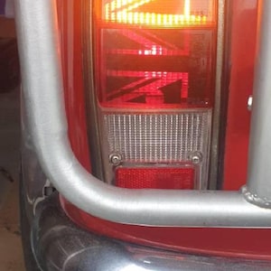 Puede incluir: Un coche rojo con un parachoques cromado y una luz trasera roja y blanca con el texto "9512" en ella.