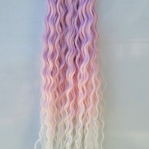 Puede incluir: Extensiones de pelo rizado ombre rosa y blanco. El pelo es ondulado y tiene un color rosa claro en la parte superior que se desvanece a blanco en la parte inferior.