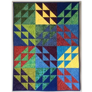 May include: A colorful quilt with a geometric pattern. The quilt features squares of various colors, including green, blue, red, and yellow. Each square is divided into triangles, creating a dynamic and visually appealing design. The quilt is likely handmade.