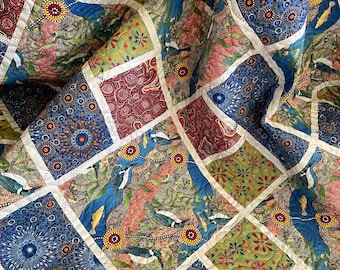 Puede incluir: Un edredón de retazos con una variedad de patrones cuadrados coloridos. El edredón presenta diseños con pájaros, motivos florales y patrones abstractos en tonos de azul, rojo, verde y marrón. Las costuras blancas delinean cada cuadrado.