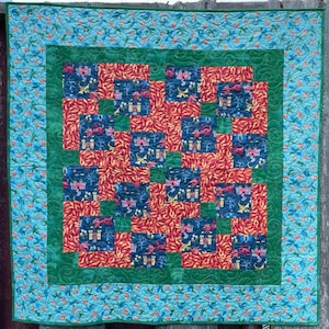 May include: A green and blue patchwork quilt with a red and orange dragon design. The quilt is made up of squares with a repeating pattern of dragons and castles.