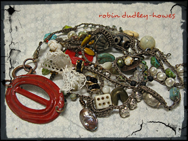 Peut inclure: Plusieurs colliers faits &agrave; la main avec diverses perles, dont des turquoises, des perles et des cristaux transparents. Les colliers sont entrelac&eacute;s avec un fermoir ovale rouge et un morceau de dentelle blanche. Le texte "robin dudley-howes" est inclus.