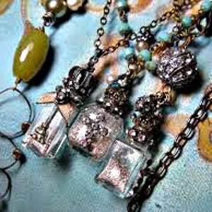 May include: Three silver and glass bottle pendant necklaces with silver and crystal embellishments. Each bottle is filled with glitter and a small silver charm.