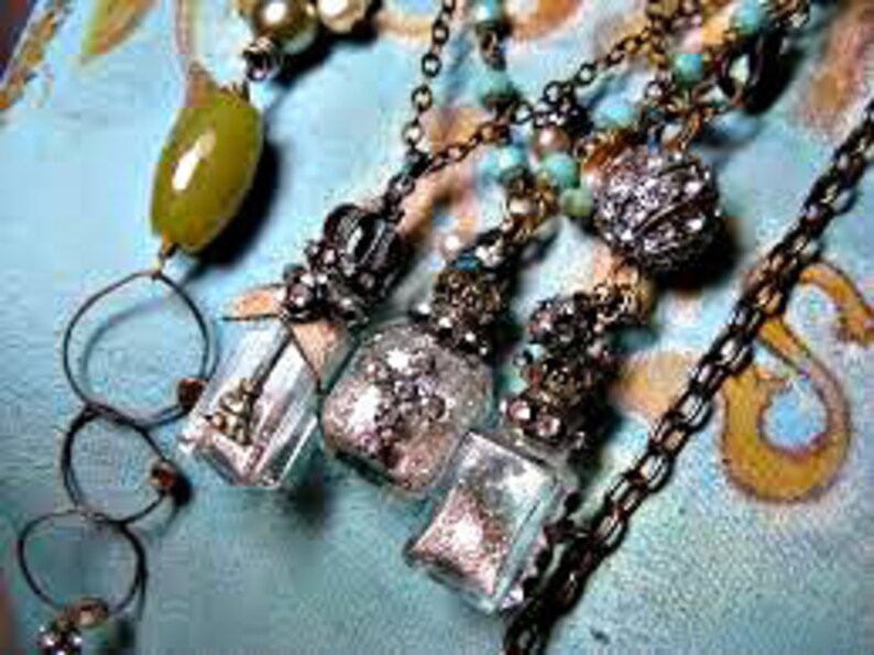 May include: Three silver and glass bottle pendant necklaces with silver and crystal embellishments. Each bottle is filled with glitter and a small silver charm.