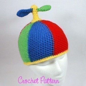 May include: A colourful crocheted hat with a propeller on top. The hat is made in shades of red, blue, green, and yellow.