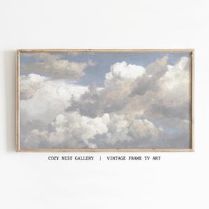 Könnte beinhalten: Gerahmtes Gemälde im Vintage-Stil mit einem bewölkten Himmel. Das Kunstwerk zeigt einen hellblauen Himmel mit flauschigen weißen und grauen Wolken. Der Rahmen hat eine hellbraune Farbe. Der Text unten lautet "COZY NEST GALLERY | VINTAGE FRAME TV ART."