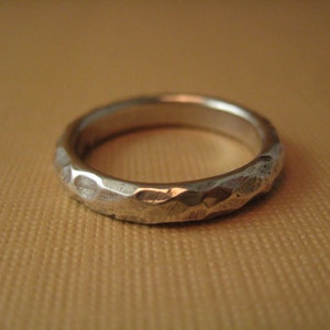 May include: A silver hammered ring with a smooth, rounded surface.