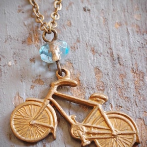 little vintage brass bicycle charm necklace. repurposed old bike charm & aqua blue czech glass bead on antiqued brass chain. ooak by val b.