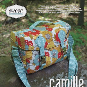 May include: A camera bag with a floral pattern in red, yellow, and light blue, featuring a top handle, an adjustable cross-body strap, and two front buckles. The bag measures 12.5 inches wide, 8 inches tall, and 5 inches deep, labeled as Camille.