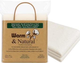 Op de afbeelding: Een verpakking Warm & Natural naaldgeperste katoenen vulling in een doorzichtige plastic zak met een bruin papieren label. Het label bevat de tekst Warm & Natural, een illustratie van katoenbollen en vermeldt de afmetingen 86 cm bij 1,14 m.