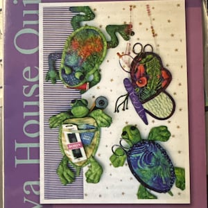 Pode incluir: Uma embalagem roxa e branca para "Just In Cases" com um design de quatro estojos em forma de tartaruga. Os estojos são verdes, azuis e estampados, com o texto "8" Glasses & Notions Cases" e "Java House Quilts".