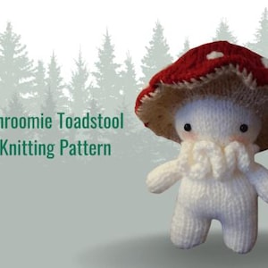 May include: A knitted mushroom figure with a red and white spotted cap and a white body. The figure has a fluffy beard and small black eyes. Text on the image reads "Shroomie Toadstool Knitting Pattern". The background features a silhouette of pine trees.