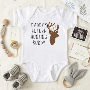 May include: A white ceramic mug with a black handle and the text "But First, Coffee" in a black, handwritten-style font. The mug is on a white surface.