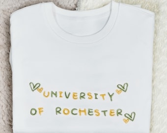 May include: White sweatshirt with green and yellow embroidered text that reads "University of Rochester" with hearts on either side of the text.