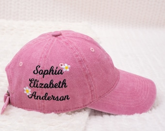 May include: Pink baseball cap with embroidered text "Sophia Elizabeth Anderson" and small white flowers.