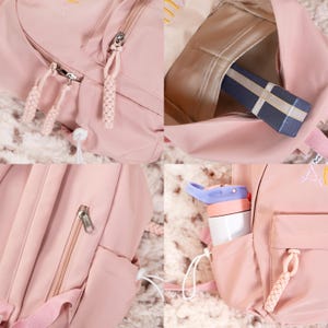 May include: A pink backpack with multiple zippered compartments and a small pocket on the front. The backpack has a white drawstring and a white zipper pull. The backpack is made of a water-resistant material.