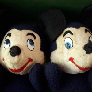 Puede incluir: Dos juguetes de peluche Mickey Mouse azules con orejas negras y caras blancas. Tienen narices negras, bocas rojas y ojos azules.