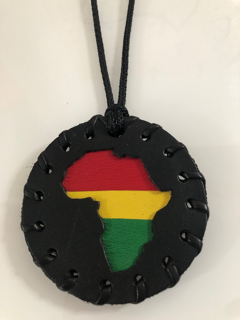 Pu&ograve; includere: Una collana in pelle nera con un ciondolo rotondo che presenta un'incisione del continente africano nei colori della bandiera panafricana: rosso, giallo e verde.