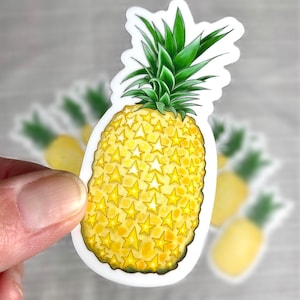 May include: A yellow pineapple sticker with a green top and a pattern of gold stars. The sticker is on a white background.