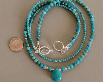 May include: A layered turquoise necklace with a teardrop pendant. The necklace features small, round turquoise beads strung together with silver-colored accents and a clasp. A U.S. dime is next to the necklace for size comparison.
