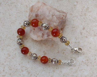 May include: A bracelet with carnelian and citrine beads and silver accents. The bracelet has a silver clasp.