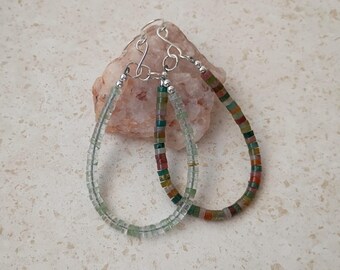 May include: A pair of hoop earrings featuring small, flat, circular beads. One earring is composed of translucent pale green beads, while the other features a multicolored pattern of red, green, and brown beads. Both have silver-toned metal hooks.