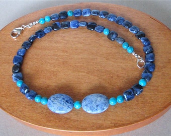 May include: A blue and turquoise gemstone necklace with a silver clasp. The necklace features oval-shaped blue stones and round turquoise stones.
