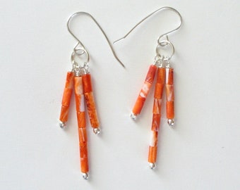 May include: A pair of dangle earrings with orange and white coral beads hanging from silver hooks.
