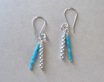 May include: A pair of silver dangle earrings with turquoise blue beads and silver beads.