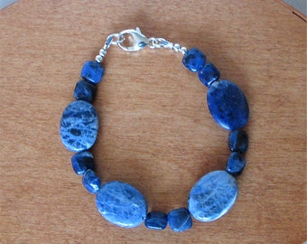 May include: A blue gemstone bracelet with oval-shaped beads and a silver clasp.