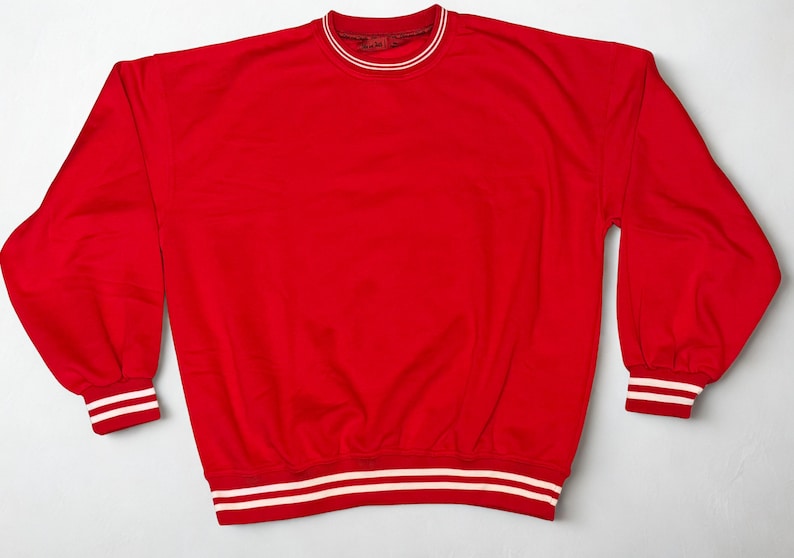 May include: A bright red sweatshirt with a crew neck and long sleeves. The collar, cuffs, and hem feature white stripes. The sweatshirt is made of a soft material and is suitable for casual wear.