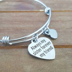 May include: Silver bangle bracelet with a heart charm that reads "Always my sister forever my friend".