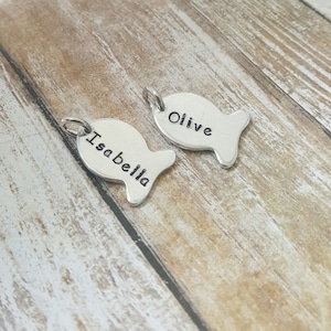 May include: Two silver fish-shaped charms with the names "Isabella" and "Olive" engraved on them.