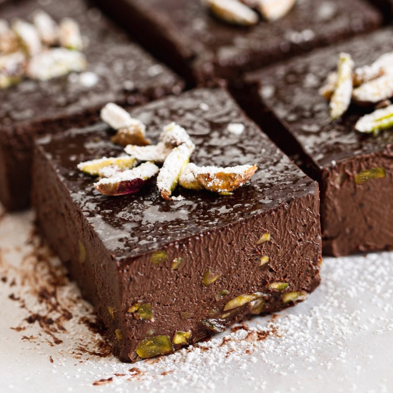 Slices of gluten-free brownies topped with nuts on a surface.