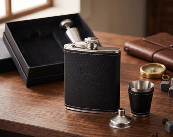 May include: A black faux leather-wrapped stainless steel flask with white stitching, accompanied by a matching small cup, a silver metal funnel, and a black presentation box with a velvet-lined interior for storage and display.
