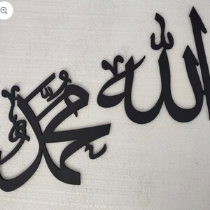 Puede incluir: Arte de pared de caligrafía negra con las palabras árabes "Allah" y "Muhammad" en un estilo decorativo.