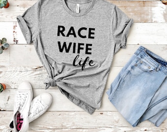 Könnte beinhalten: Graues T-Shirt mit dem Aufdruck "RACE WIFE life" in Schwarz.
