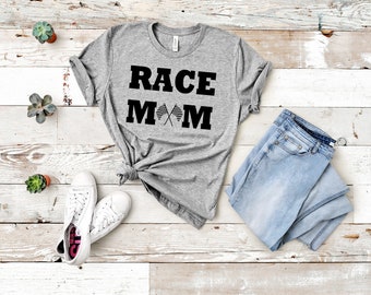 Könnte beinhalten: Graues T-Shirt mit dem Text "RACE MOM" in schwarzen Buchstaben. Das "M" ist mit gekreuzten karierten Flaggen verziert.