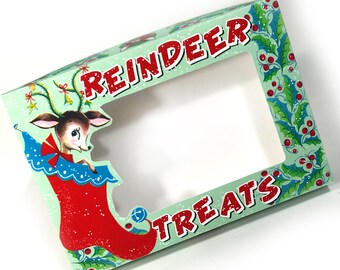 Puede incluir: Una tarjeta de Navidad verde y roja con un reno en una media y las palabras "Reindeer Treats".