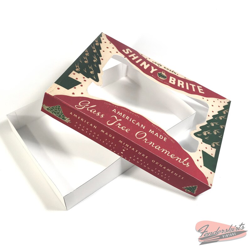 May include: A red and green box with a clear plastic window. The box is labeled "Shiny Brite American Made Glass Tree Ornaments".