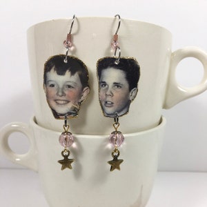 May include: A pair of dangle earrings featuring vintage photos of boys' faces, pink glass beads, and gold star charms.