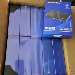 May include: A cardboard box filled with several blue V6 MAX Smart Media Player boxes and several other blue boxes. The V6 MAX box has the vSeeBox logo and product information. The boxes are in a brown cardboard box.