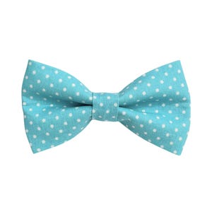 May include: A turquoise bow tie with a white polka dot pattern. The bow tie is made of fabric and is tied in a classic bow shape. The background is plain white.