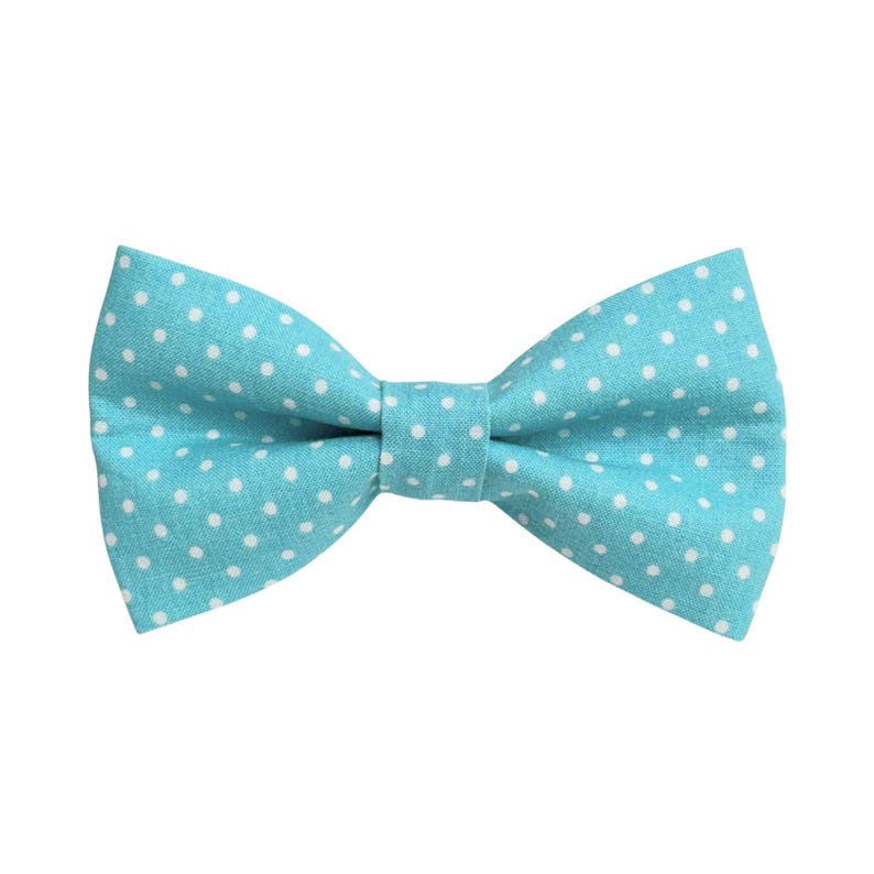 May include: A turquoise bow tie with a white polka dot pattern. The bow tie is made of fabric and is tied in a classic bow shape. The background is plain white.