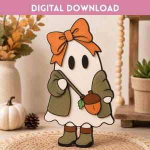 Puede incluir: Un recorte de madera plano de un fantasma con un lazo naranja, un cárdigan verde oscuro y botas verde oscuro. El fantasma lleva un bolso con forma de bellota con una tapa marrón y base naranja. El texto DIGITAL DOWNLOAD aparece en la parte superior.