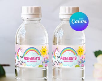 Könnte beinhalten: Zwei durchsichtige Plastikwasserflaschen mit weißen Verschlüssen, jeweils mit einem bedruckbaren Etikett mit Einhorn-, Regenbogen-, Sonnen- und Schlossgrafik. Der Text auf dem Etikett lautet Ashley's 3rd Birthday. Ein rundes blau-violettes Canva-Logo ist zu sehen.